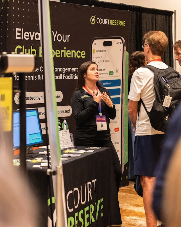 Woman talking to attendees at a CourtReserve booth